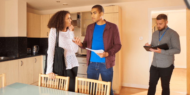 What Are Contingencies? One person asking can a buyer back out before closing to another person in a kitchen with an agent nearby.